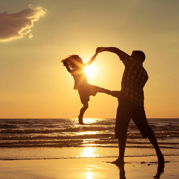 Pai e filho brincando na praia na hora do pôr do sol . — Fotografia de Stock