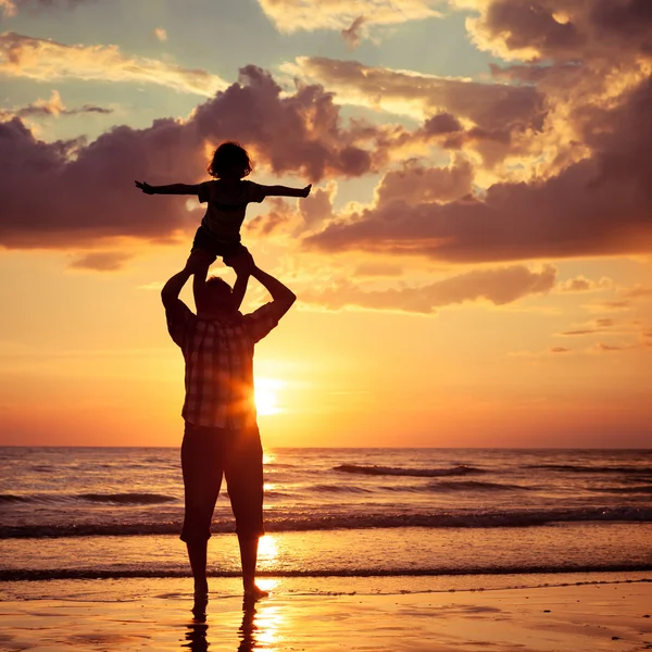 Otec a syn hraje na pláži při západu slunce. — Stock fotografie