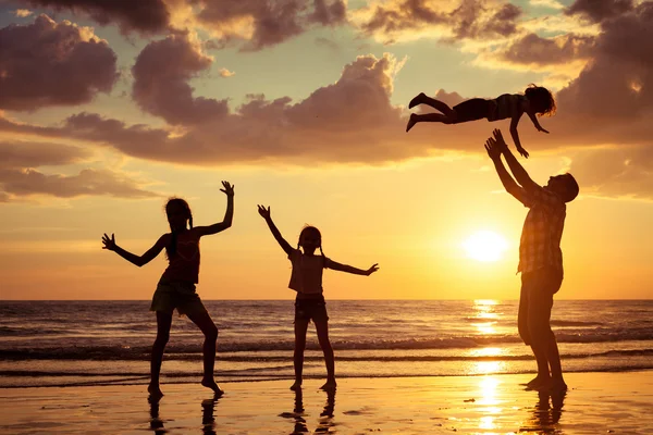 Pai e crianças brincando na praia na hora do pôr do sol . — Fotografia de Stock