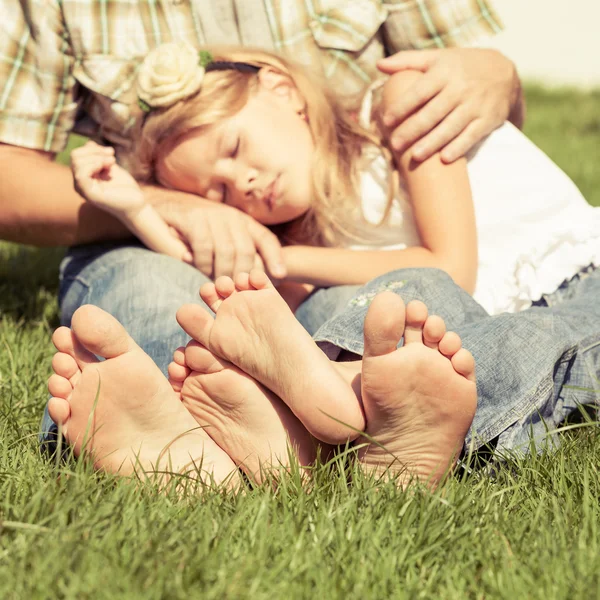 Vader en dochter zittend op het gras op het moment van de dag. — Stockfoto