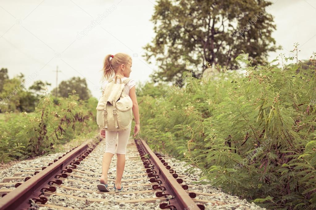 Happy little girl walking on the railway