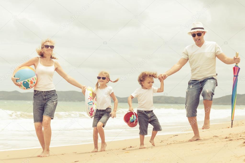 Happy family dancing on the beach at the day time.