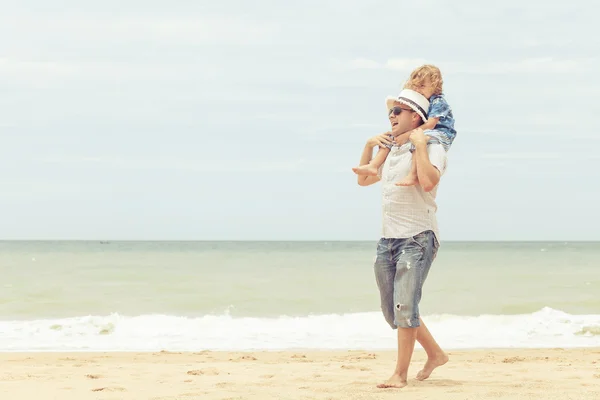 Far och son som spelar på stranden på dagarna. — Stockfoto