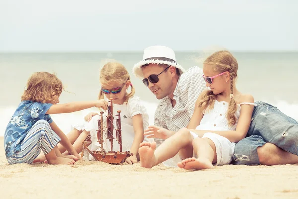 Padre e figli che giocano sulla spiaggia durante il giorno . — Foto Stock