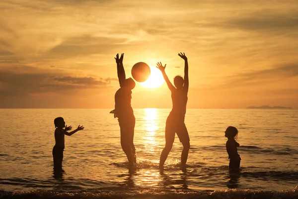 Silhouette of happy family who playing on the beach at the sunse — Stock Photo, Image