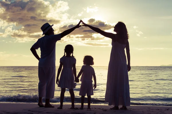 Silueta de familia feliz que juega en la playa al atardecer — Foto de Stock