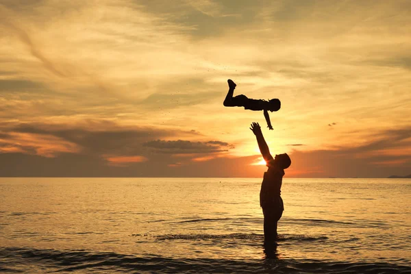 Baba ve oğul sahilde günbatımı anda oynamak.