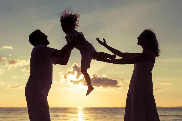 Silhouet van gelukkige familie die spelen op het strand bij de sunse — Stockfoto