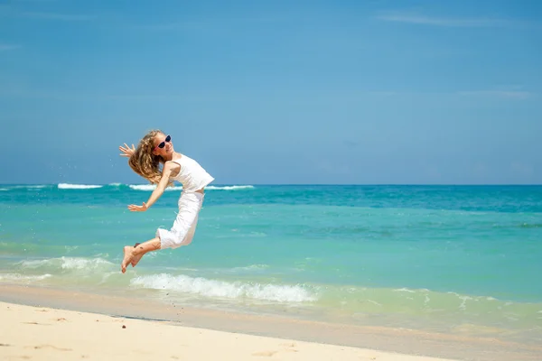 少女在夏天 vaca 的蓝色的大海岸边沙滩上跳跃 — 图库照片