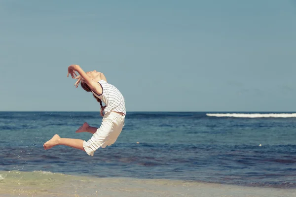 Teen flicka hoppa på stranden vid blå havet — Stockfoto