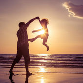 Vater und Sohn spielen am Strand bei Sonnenuntergang.