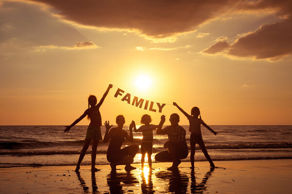 Happy family standing on the beach at the sunset time. 