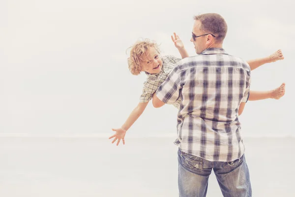 Far och son som spelar på stranden på dagarna. — Stockfoto