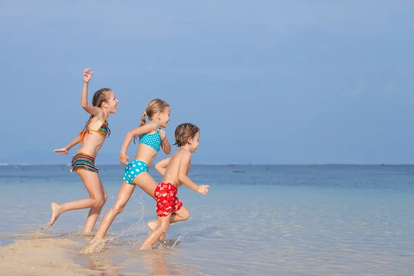 Drei glückliche Kinder spielen am Strand — Stockfoto