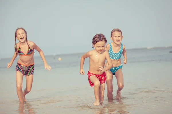 Trzy szczęśliwe dzieci bawiące się na plaży — Zdjęcie stockowe