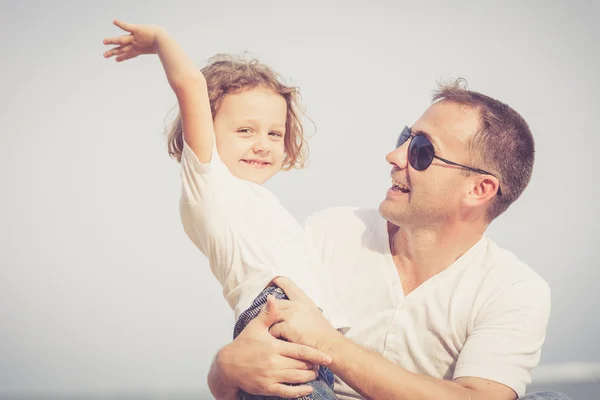 Vader en zoon spelen op het strand op het moment van de dag. — Stockfoto