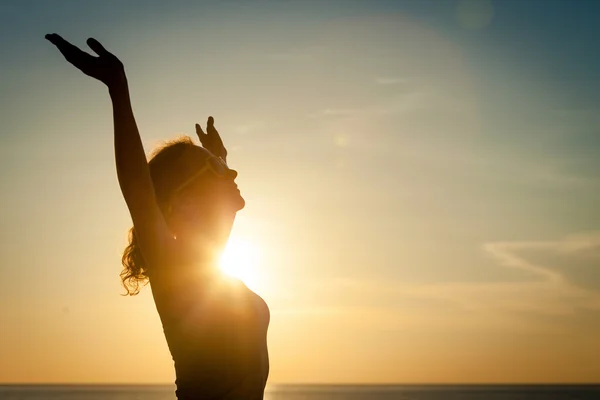 Vrouw open armen onder de zonsopgang op de zee — Stockfoto