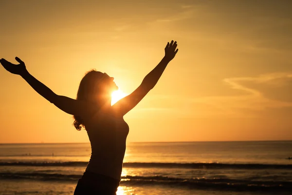 Vrouw open armen onder de zonsopgang op de zee — Stockfoto