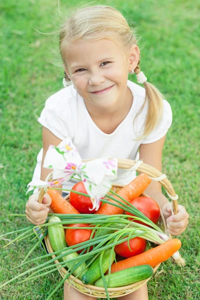 Szczęśliwa dziewczynka siedzi na trawie z koszem vegetabl — Zdjęcie stockowe