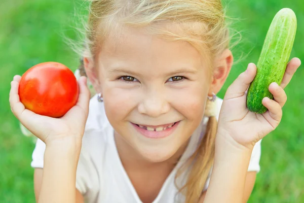 Bonne petite fille assise sur l'herbe avec un légume à la — Photo