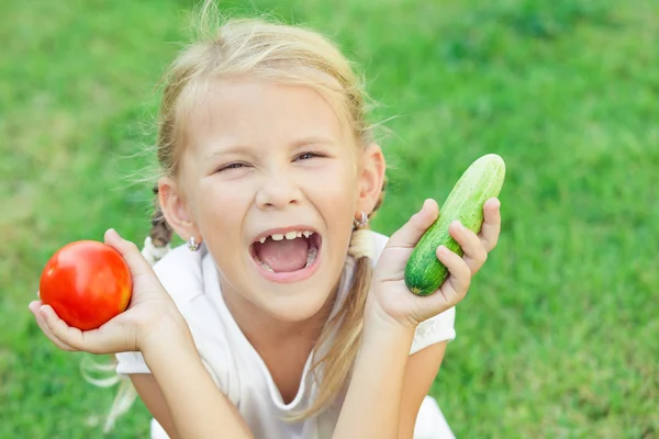 Gelukkig meisje, zittend op het gras met een groenten bij de — Stockfoto