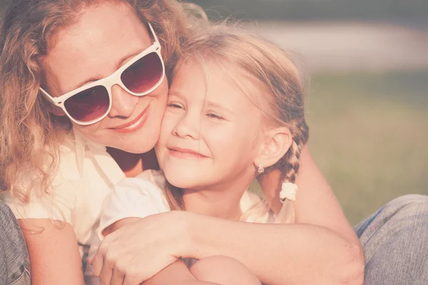 Mother and daughter playing on the grass at the day time. — Stock Photo, Image