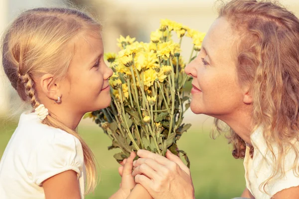 Mother and daughter playing on the grass at the day time. — Stock Photo, Image