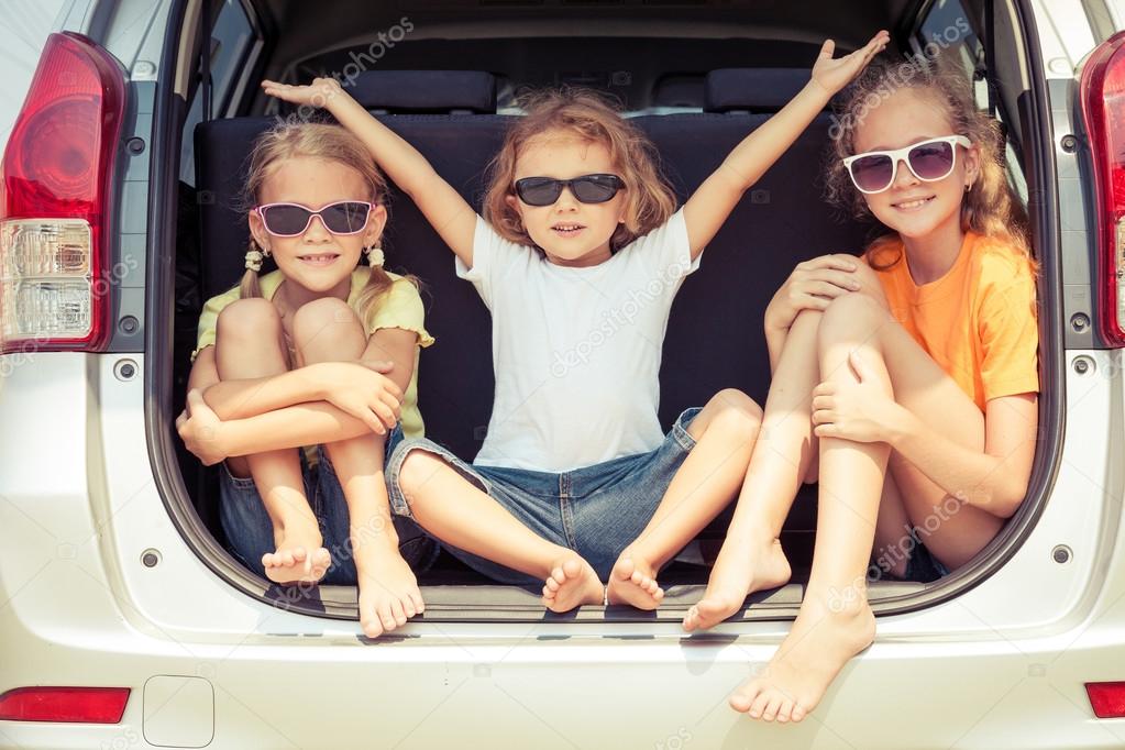 Happy brother and his two sisters are sitting in the car