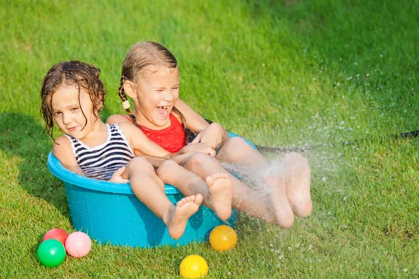 Fratello e sorella giocare con acqua vicino a una casa — Foto Stock