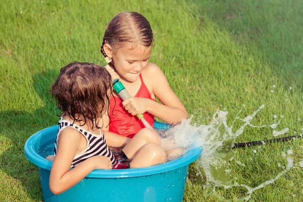 Broer en zus spelen met water in de buurt van een huis — Stockfoto