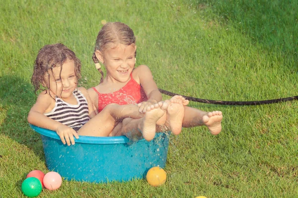 Broer en zus spelen met water in de buurt van een huis — Stockfoto