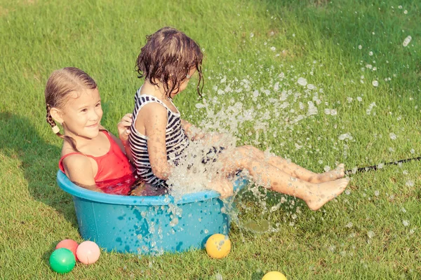 Broer en zus spelen met water in de buurt van een huis — Stockfoto