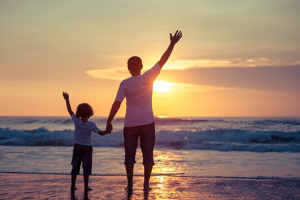 Père et fils jouant sur la plage au coucher du soleil . — Photo