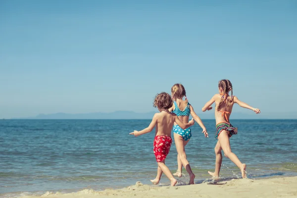 Dos hermanas y hermano jugando en la playa — Foto de Stock