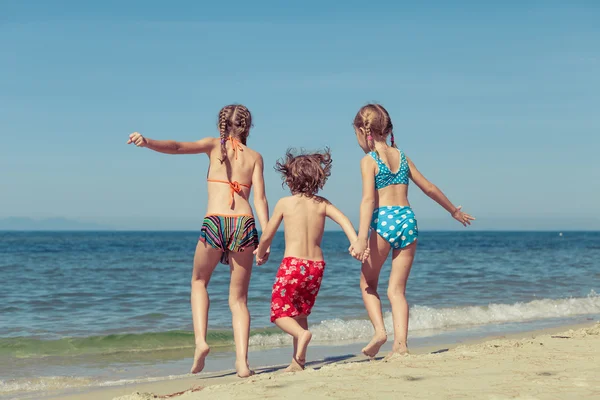 Twee zussen en broer spelen op het strand — Stockfoto