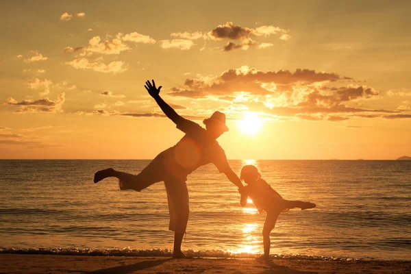Baba ve oğul sahilde günbatımı anda oynamak. — Stok fotoğraf