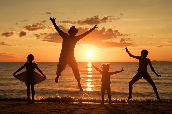 Pai e crianças brincando na praia na hora do pôr do sol . — Fotografia de Stock