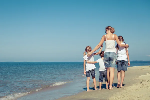 Moeder en kinderen spelen op het strand op het moment van de dag. — Stockfoto