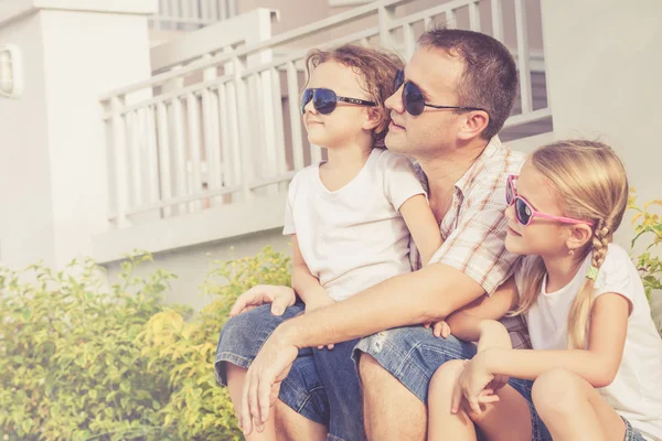 Vader en kinderen spelen in de buurt van een huis op het moment van de dag. — Stockfoto