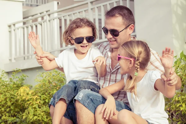 Vader en kinderen spelen in de buurt van een huis op het moment van de dag. — Stockfoto