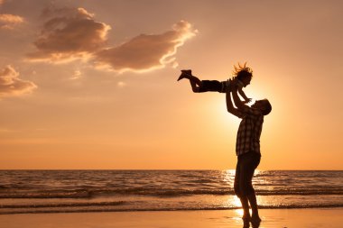 Baba ve oğul sahilde günbatımı anda oynamak.