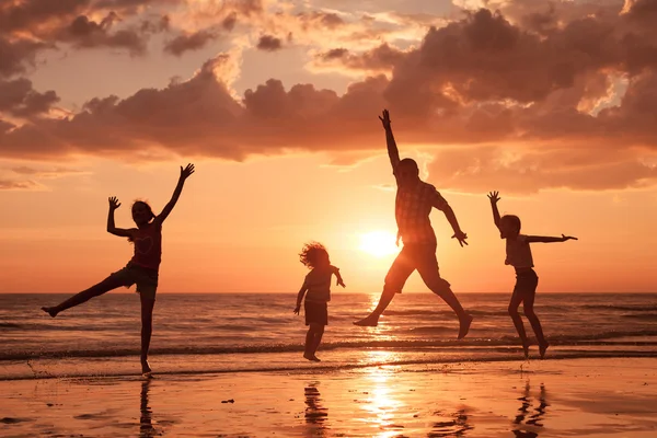 Far och barn som leker på stranden vid solnedgången tid. — Stockfoto