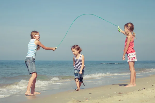 Två systrar och bror spelar på stranden — Stockfoto