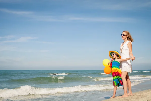 Madre e hija jugando con globos en la playa en el da —  Fotos de Stock