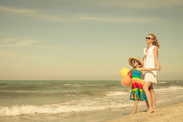 Madre e hija jugando con globos en la playa en el da —  Fotos de Stock