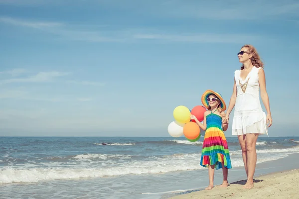 Madre e figlia che giocano con i palloncini sulla spiaggia al da — Foto Stock