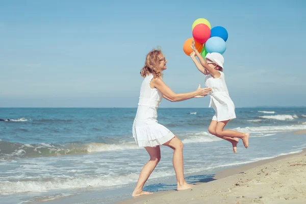 Mãe e filha brincando com balões na praia na da — Fotografia de Stock