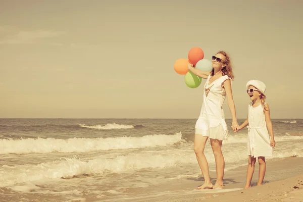Mãe e filha brincando com balões na praia na da — Fotografia de Stock