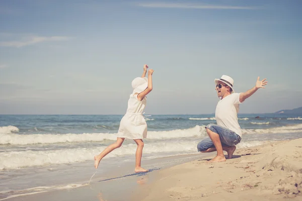 Far och dotter spelar på stranden på dagarna. — Stockfoto