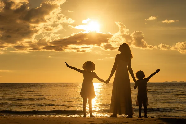 Mère et enfants debout sur la plage au coucher du soleil . — Photo